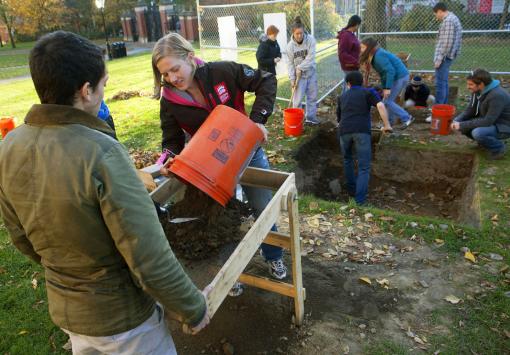 Five gallons of possibility - Sophomore Monica Roth delivers a budket of excavated dirt to the sifter, part of a systematic search for pottery sherds, bits of brick, or any other evidence of an 18th-century structure.